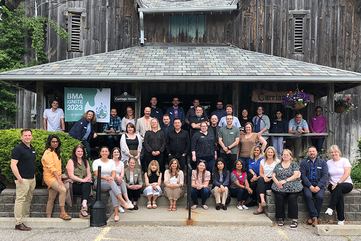 Group of brokers, facilitators and CAA Associates who participated in BMA Ignite 2023, posing for a group shot in front of an old barn.