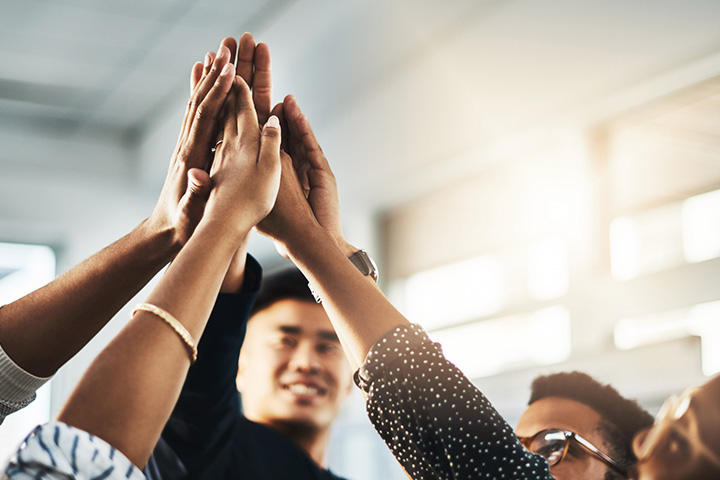 A group of 4 work colleagues doing a group high-five.