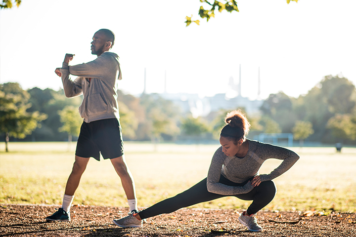 A man and a woman in a field stretching before exercise