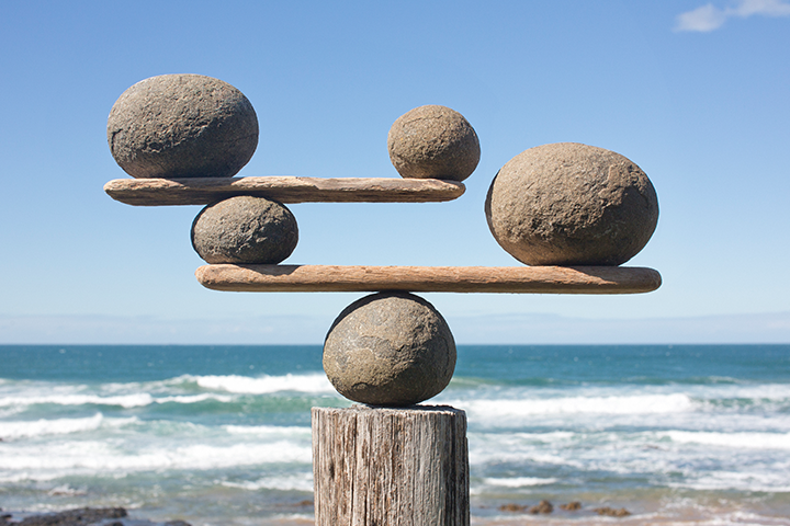 5 large stones balancing on 2 planks, with the ocean in the background.