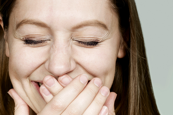 A woman laughing with her hands over her mouth