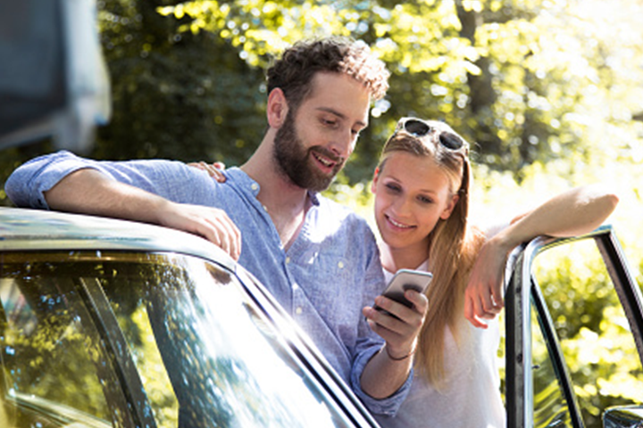 Young couple using CAA My pace app on their mobile phone. 