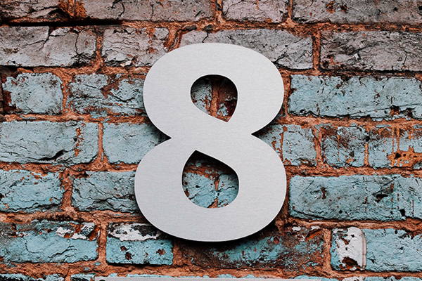 A silver metal number 8 against an old brick wall background