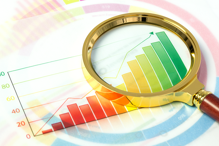 A magnifying glass laying on top of a piece of paper with a colourful graph suggesting growth.