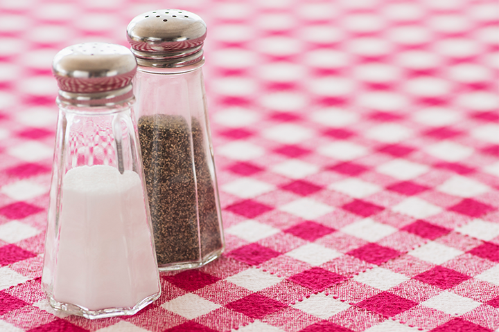 A pair of salt and pepper shakers sitting on a table with a red checkered tablecloth.