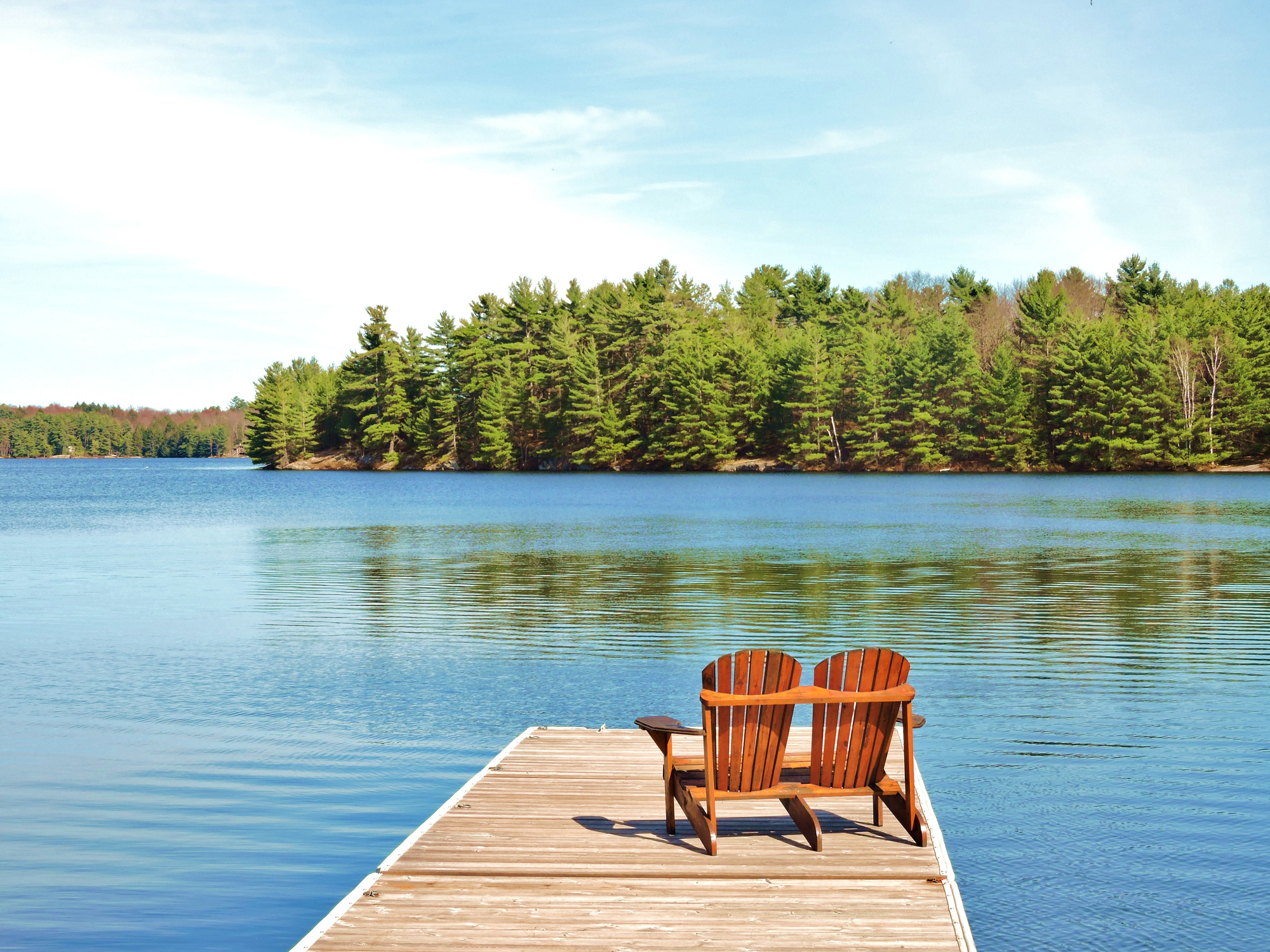 Double beach chair on a dock overlooking a lake.