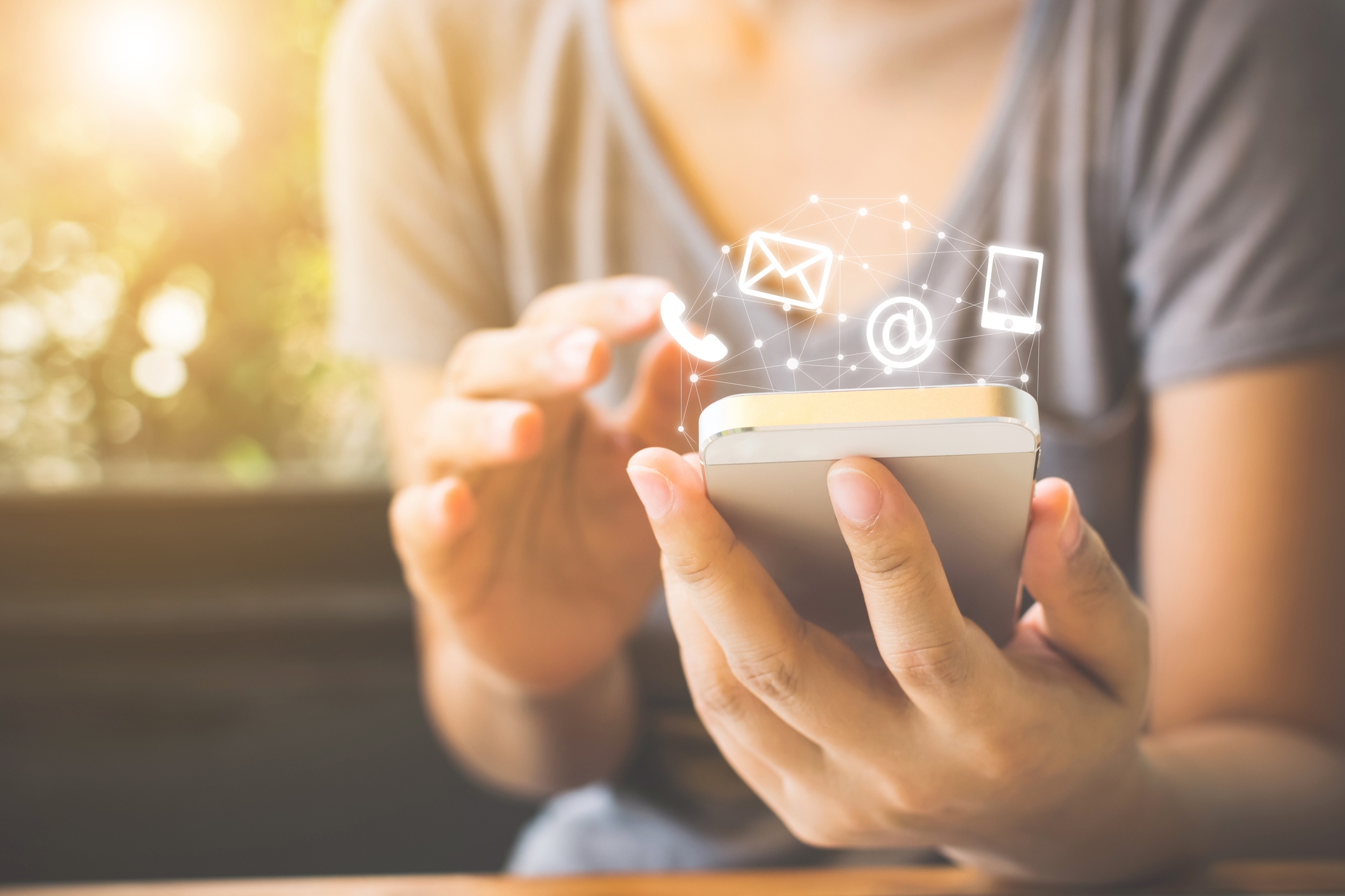 A woman holding a smartphone and illustration depicting email and phone icons i.e. demonstrating marketing trends.