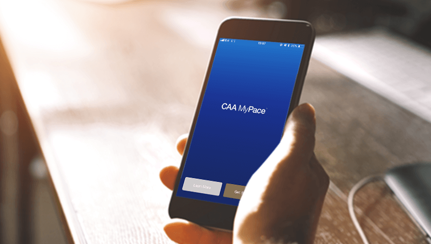 Holding a smart phone and using CAA Mypace application.