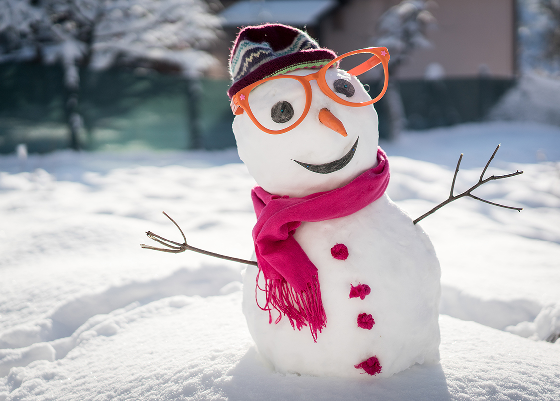 A snowman wearing orange glasses, pink scarf and a beanie